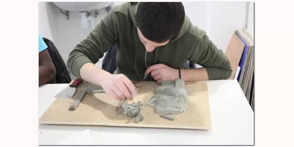 Miniature d'un jeune réalisant un bas-relief en carton pâte au cours de l'atelier d'Arts plastiques avec Karine Bracq